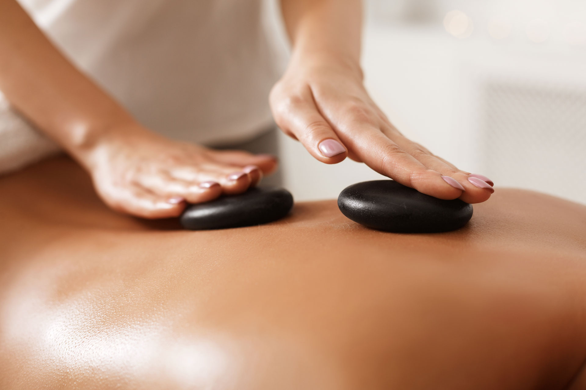 masseur-doing-back-hot-stone-massage-closeup-4NALQE2.jpg